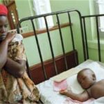 A mother next to her child in a hospital bed with measles.