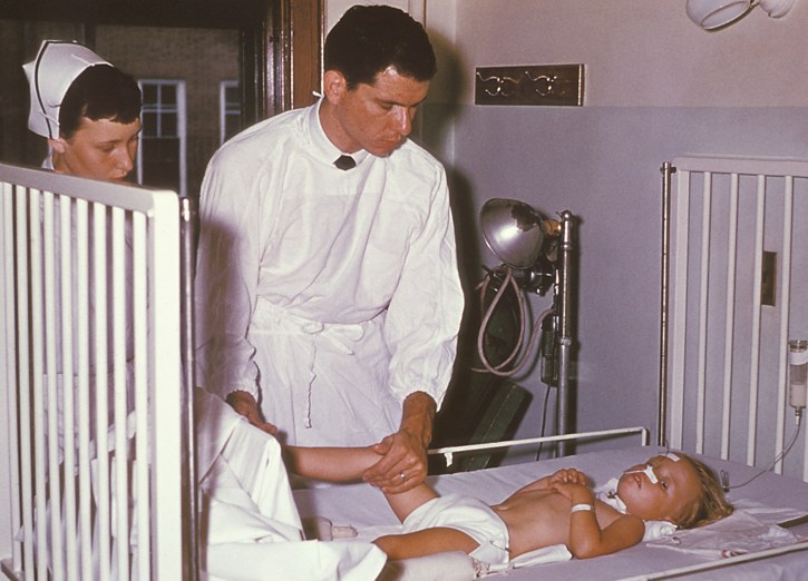 Child with polio in a hospital, tended to by a doctor and nurse in Rhode Island 1960.