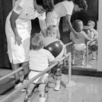 Two children with polio receiving physical therapy working with therapits.