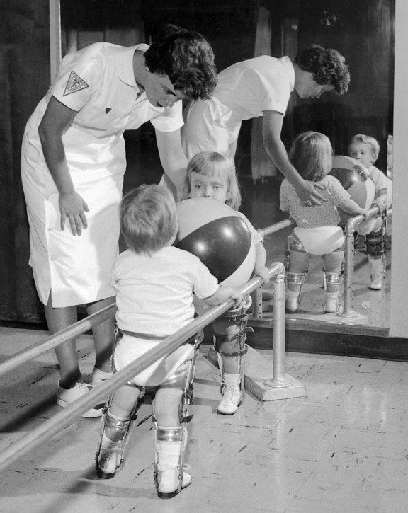 Two children with polio receiving physical therapy working with therapits.