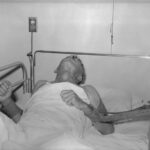 Hospitalized human rabies victim in restraints in a hospital bed.